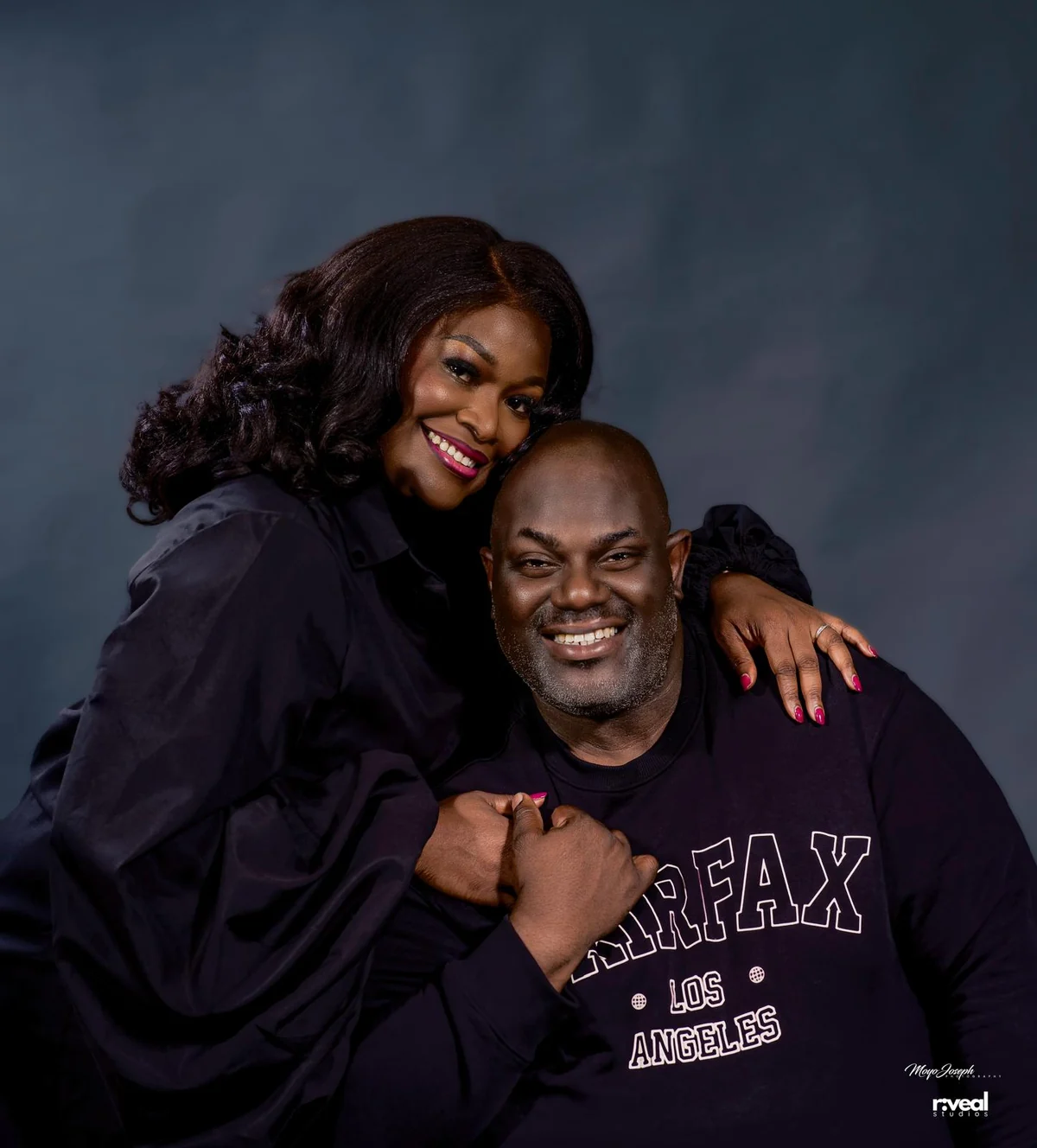Tayo and Itee smiling together, Itee's arms around Tayo's shoulders